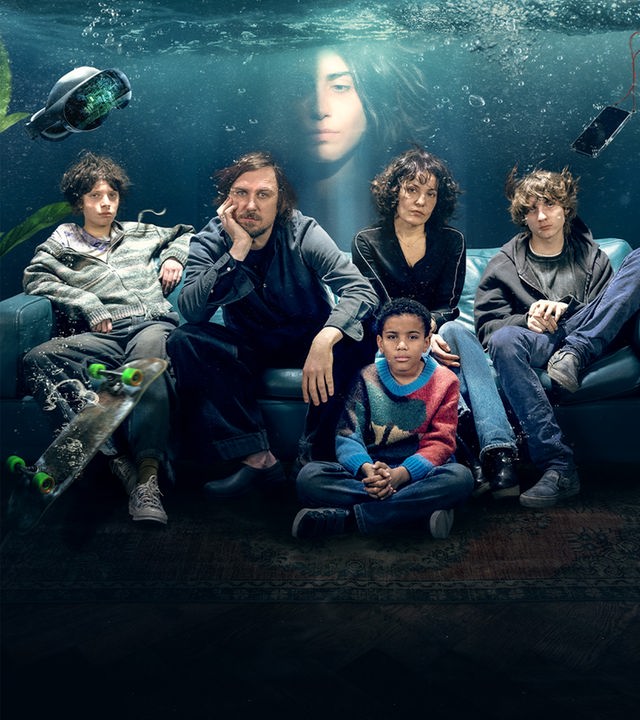 Tim, Milena, die gemeinsamen Zwillinge Frieda und Jon sowie Milenas Sohn Dio sitzen gemeinsam auf einem Sofa in ihrem Wohnzimmer. Die gesamte Szene befindet sich allerdings unter Wasser. In der Wasserkante über ihnen sieht man schemenhaft das Gesicht der Haushälterin Farrah. 
