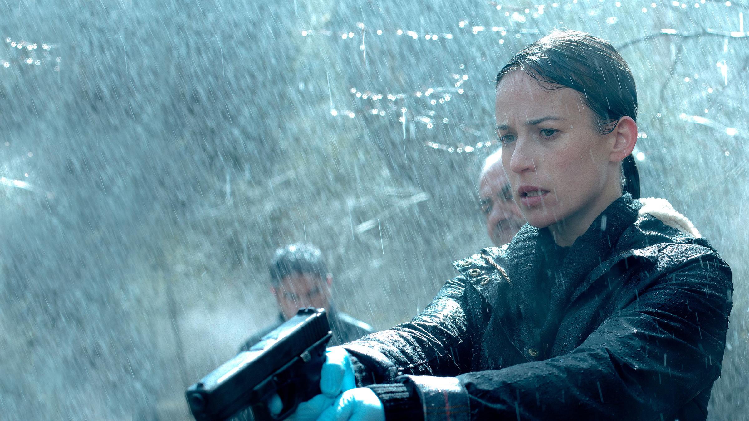 "Das Tal der toten Mädchen": Amaia Salazar (Marta Etura) steht mit gezogener Waffe im Wald und blickt nach unten.