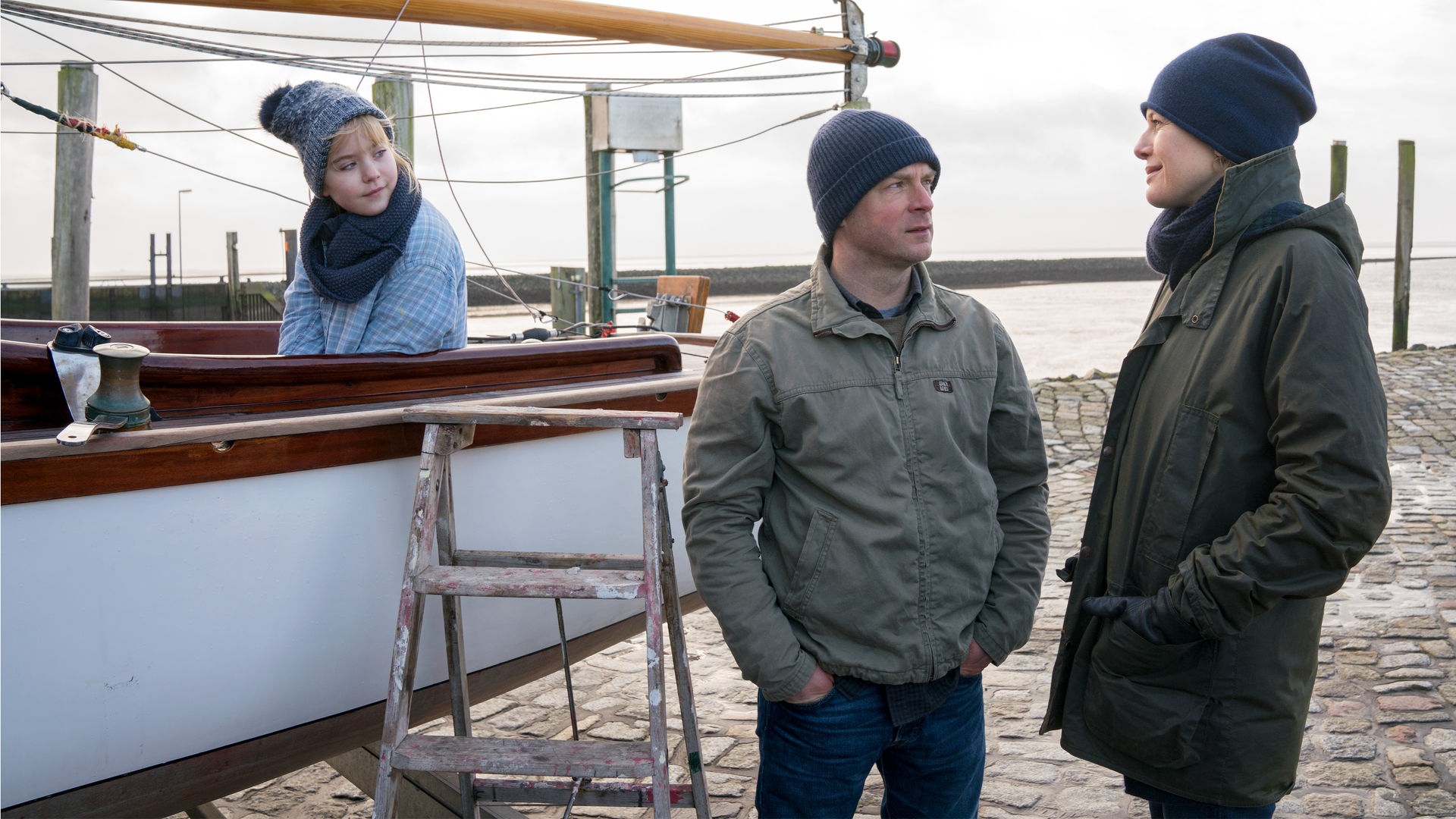 Am Ufer. Nina (Philine Steuer) sitzt auf dem Boot, neben dem Sven (Hinnerk Schönemann) steht und sich mit Anne (Ina Weisse) unterhält.