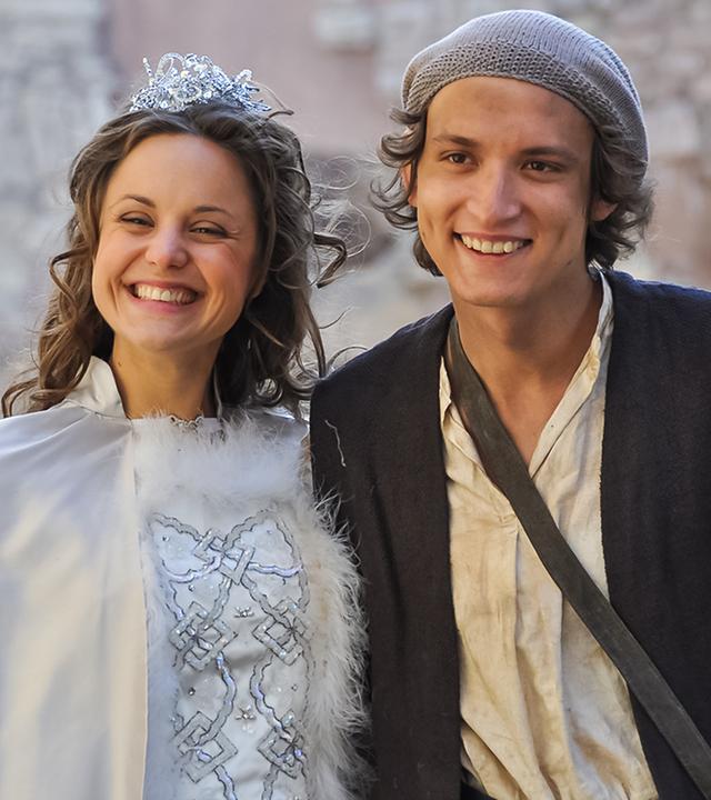 Hans (rechts) und die Königstochter (links neben ihm) strahlen vor Glück. Der Hintergrund ist hell verschwommen.