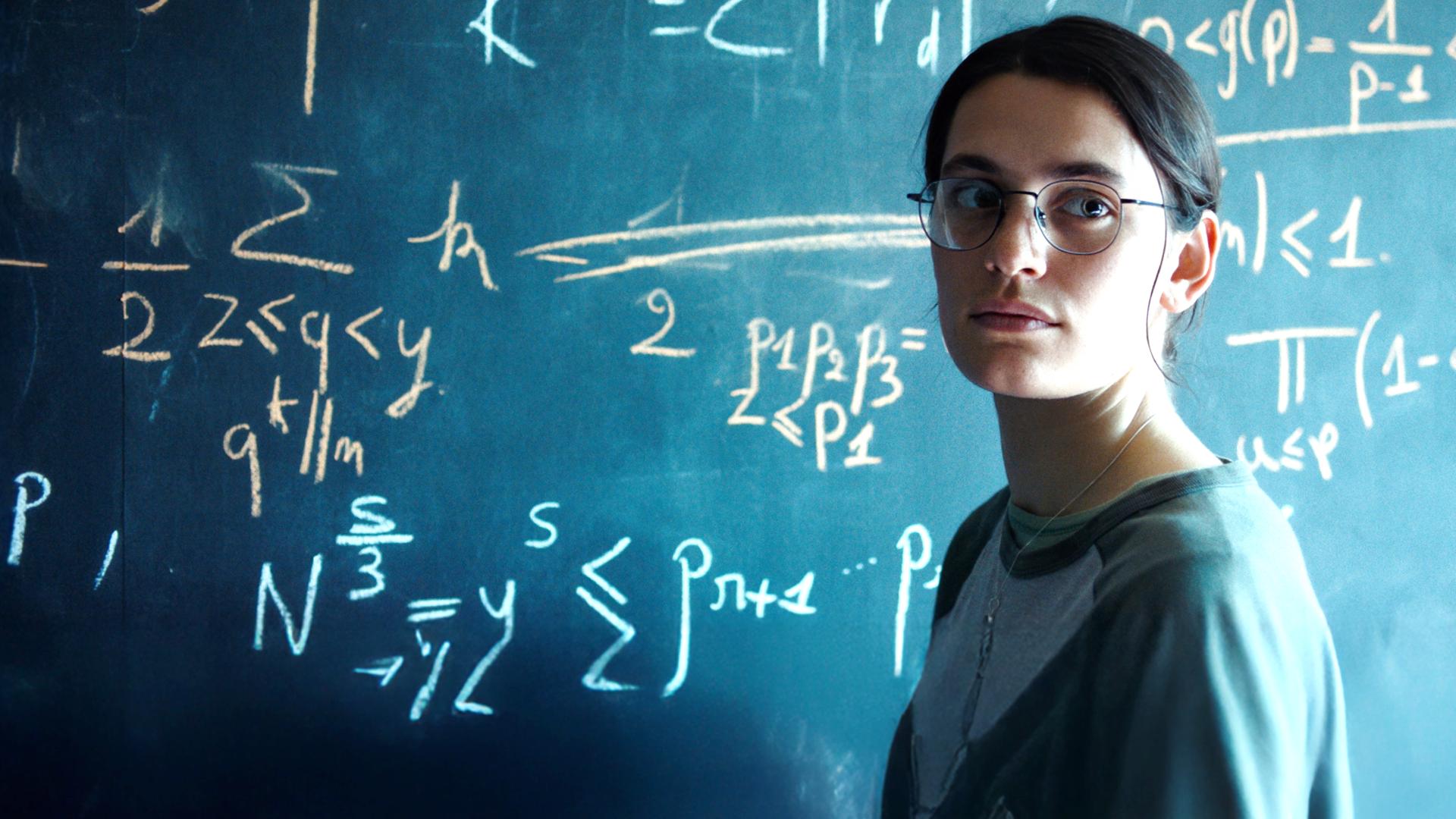 Die Pariser Doktorandin Marguerite (Ella Rumpf) lebt für die Mathematik. "Die Gleichung ihres Lebens": Nahaufnahme: Marguerite (Ella Rumpf) steht neben einer Tafel voll mathematischer Formeln und blickt auf etwas hinter der Kamera.