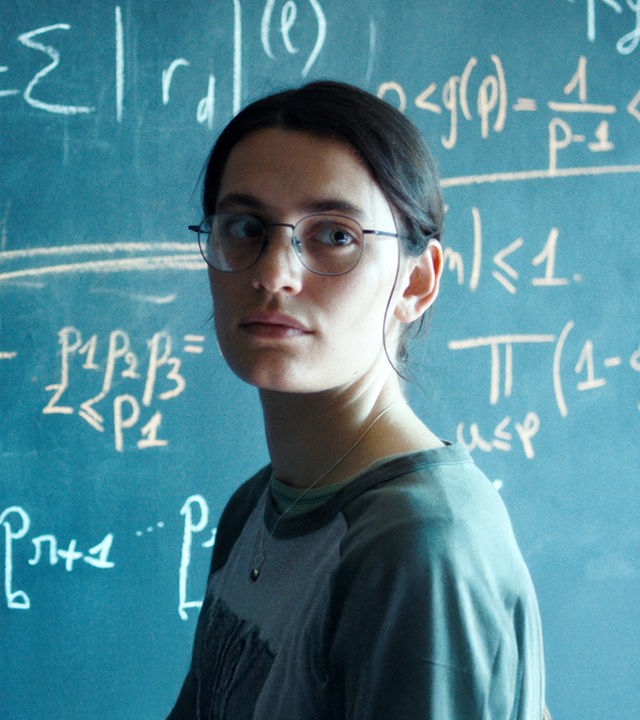 Die Pariser Doktorandin Marguerite (Ella Rumpf) lebt für die Mathematik. "Die Gleichung ihres Lebens": Nahaufnahme: Marguerite (Ella Rumpf) steht neben einer Tafel voll mathematischer Formeln und blickt auf etwas hinter der Kamera.