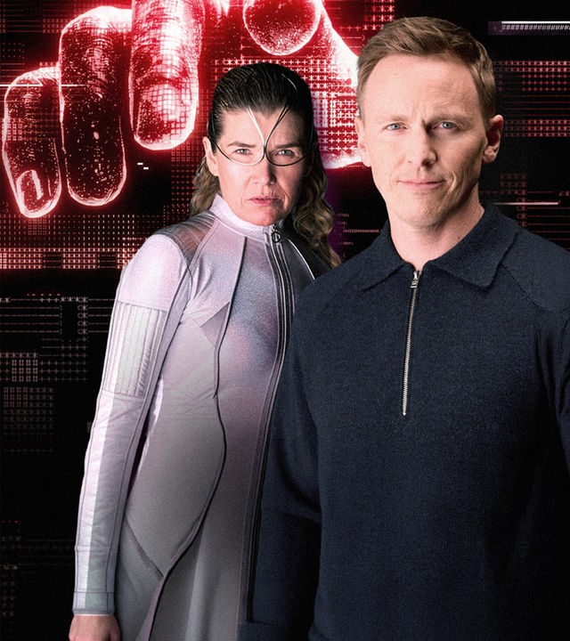 Jochen Breyer steht neben einer futuristisch gekleideten Frau. Im Hintergrund zeigt eine projizierte Hand auf den Zuschauer.