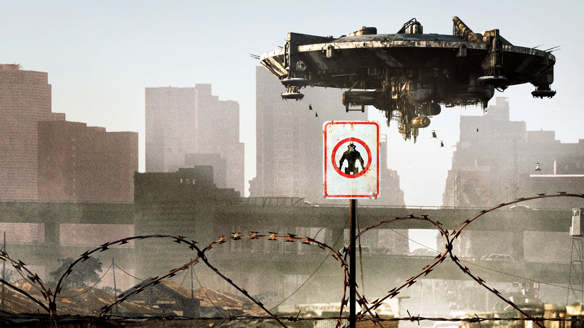 Plakatmotiv zum FIlm "District 9": Ein Raumschiff schwebt über einem mit Stacheldraht umzäunten Stadtgebiet.