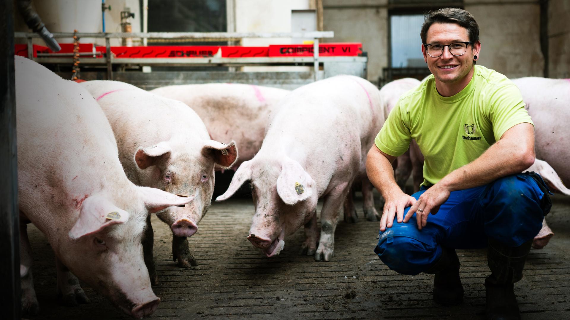 Simon Donhauser mit einem Ferkel in der Hand.