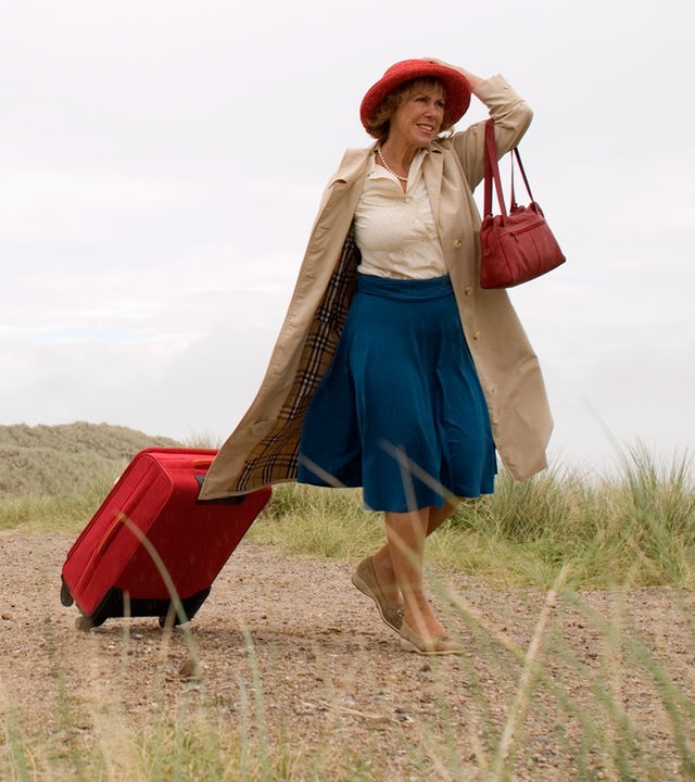 Auf der Insel Sylt läuft Inge (Gaby Dohm) an einem Leuchtturm vorbei. Sie zieht mit der rechten Hand einen Koffer hinter sich her und hält mit der anderen Hand ihren Hut auf dem Kopf fest.