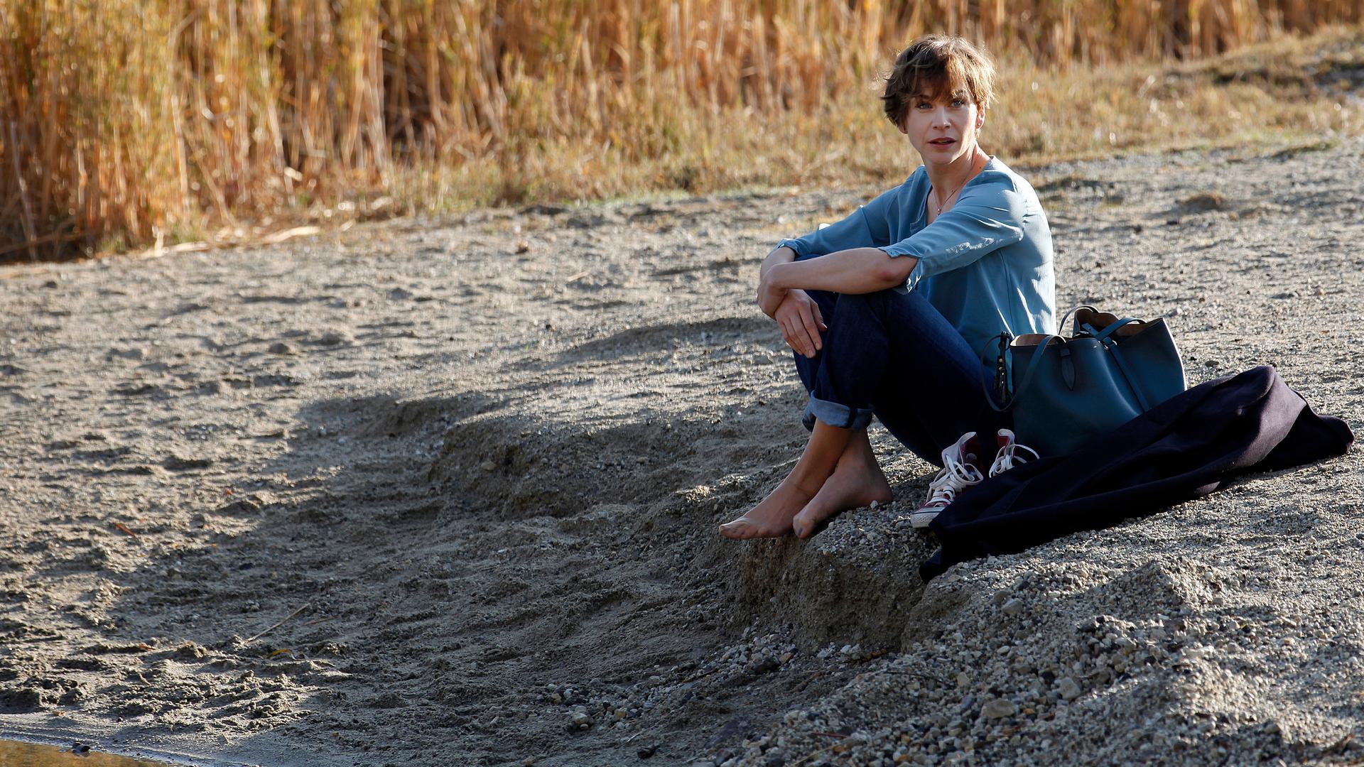 Vicky (Christiane Paul) sitzt am Ufer eines Sees.