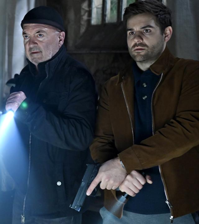 Otto Garber (Florian Martens) und Nils Makowski (Lucas Reiber) stehen in einer dunklen Lagerhalle.