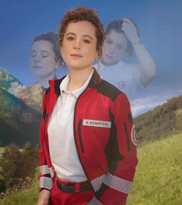 Rettungssanitäterin Elli steht vor der sommerlichen Bergkulisse des Karwendelgebirges. Sie sieht lächelnd den Zuschauer an. Links und rechts von ihrem Kopf sieht man ihr Gesicht noch einmal mit verschiedenen Gesichtsausdrücken - einmal mit geschlossenen Augen und einmal sorgenvoll mit der Hand in ihren Haaren. 