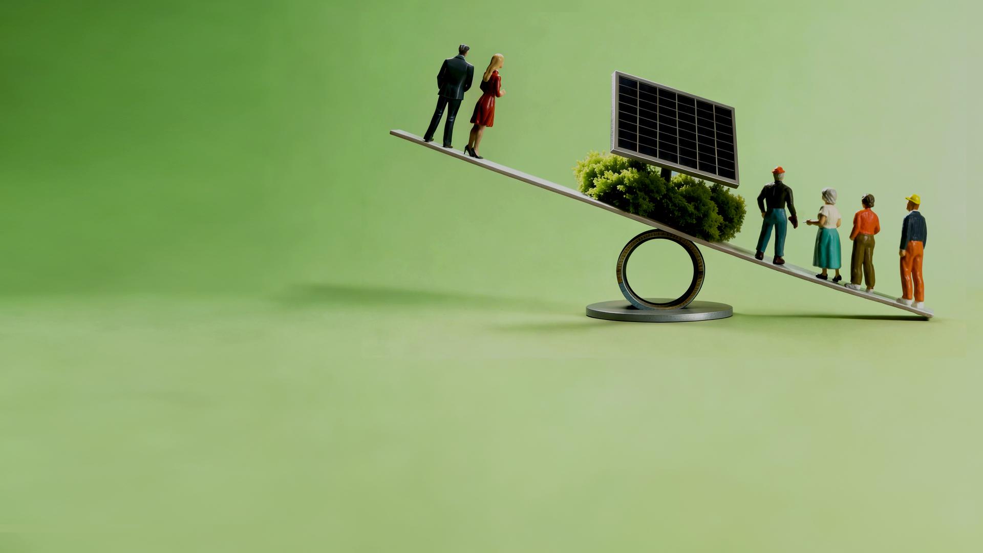 Waage mit Figuren an beiden Enden. In der Mitte ist eine Solarzelle zu sehen.