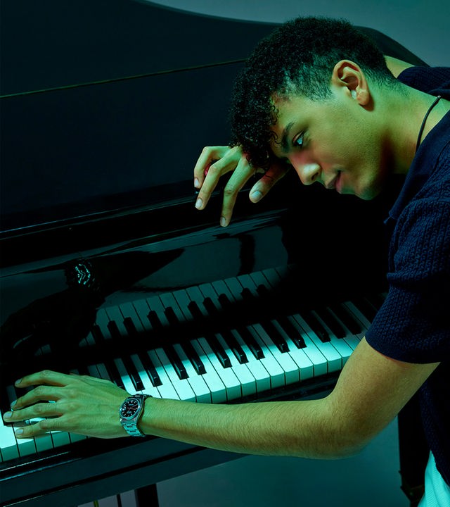 Auf dem Bild ist ein Pianist zu sehen, der seinen Kopf auf einen Flügel lehnt.