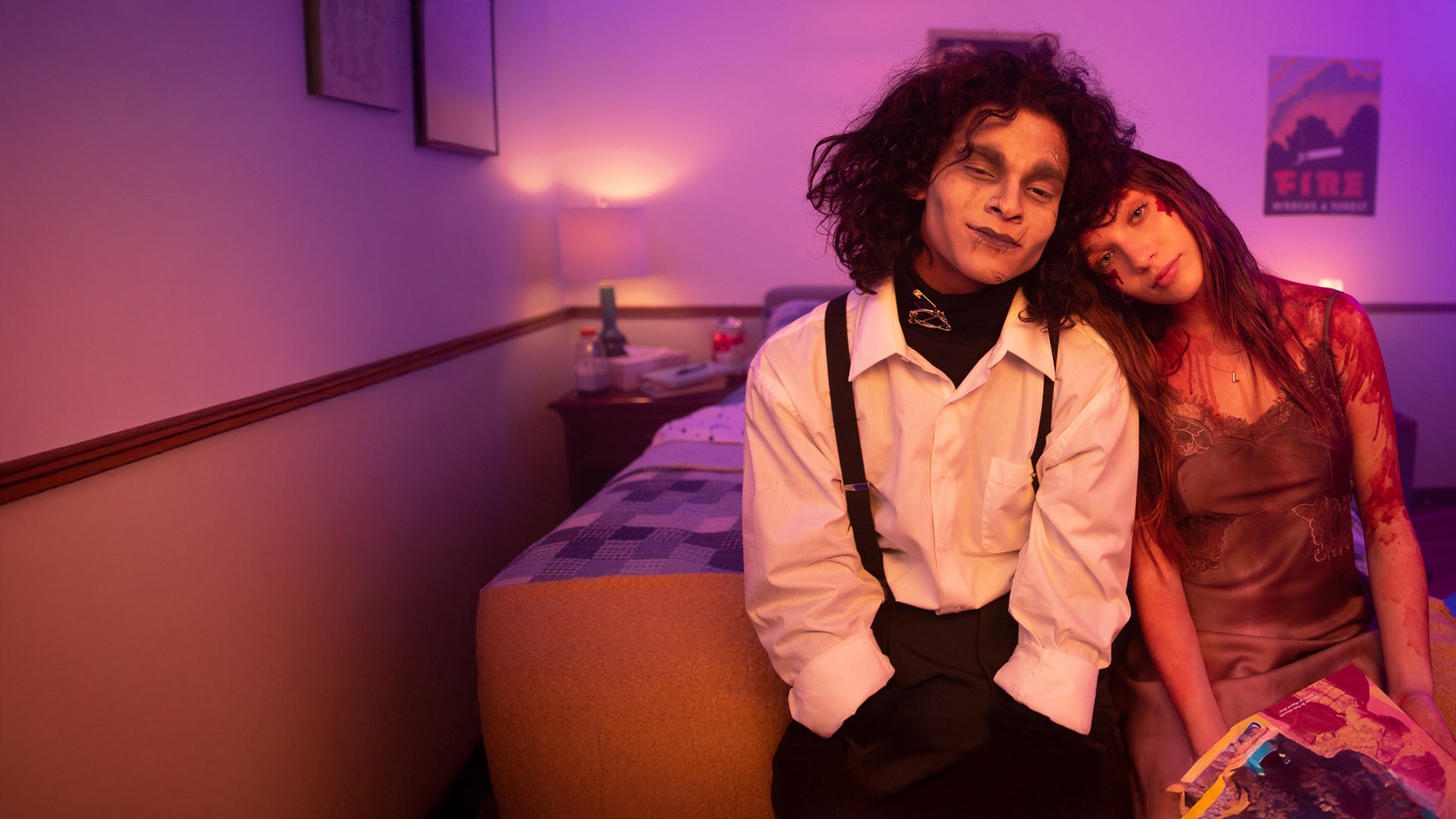  Adam (D'Pharaoh Woon-A-Tai) und Lindy (Maddie Ziegler) sitzen lächelnd nebeneinander auf einem Bett. Er ist als Edward mit den Scherenhänden kostümiert, sie als blutüberströmte Carrie