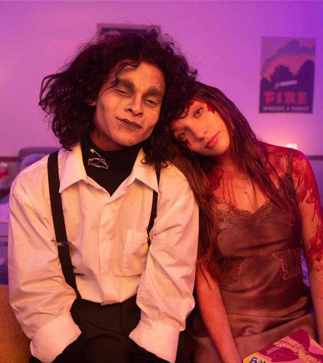  Adam (D'Pharaoh Woon-A-Tai) und Lindy (Maddie Ziegler) sitzen lächelnd nebeneinander auf einem Bett. Er ist als Edward mit den Scherenhänden kostümiert, sie als blutüberströmte Carrie