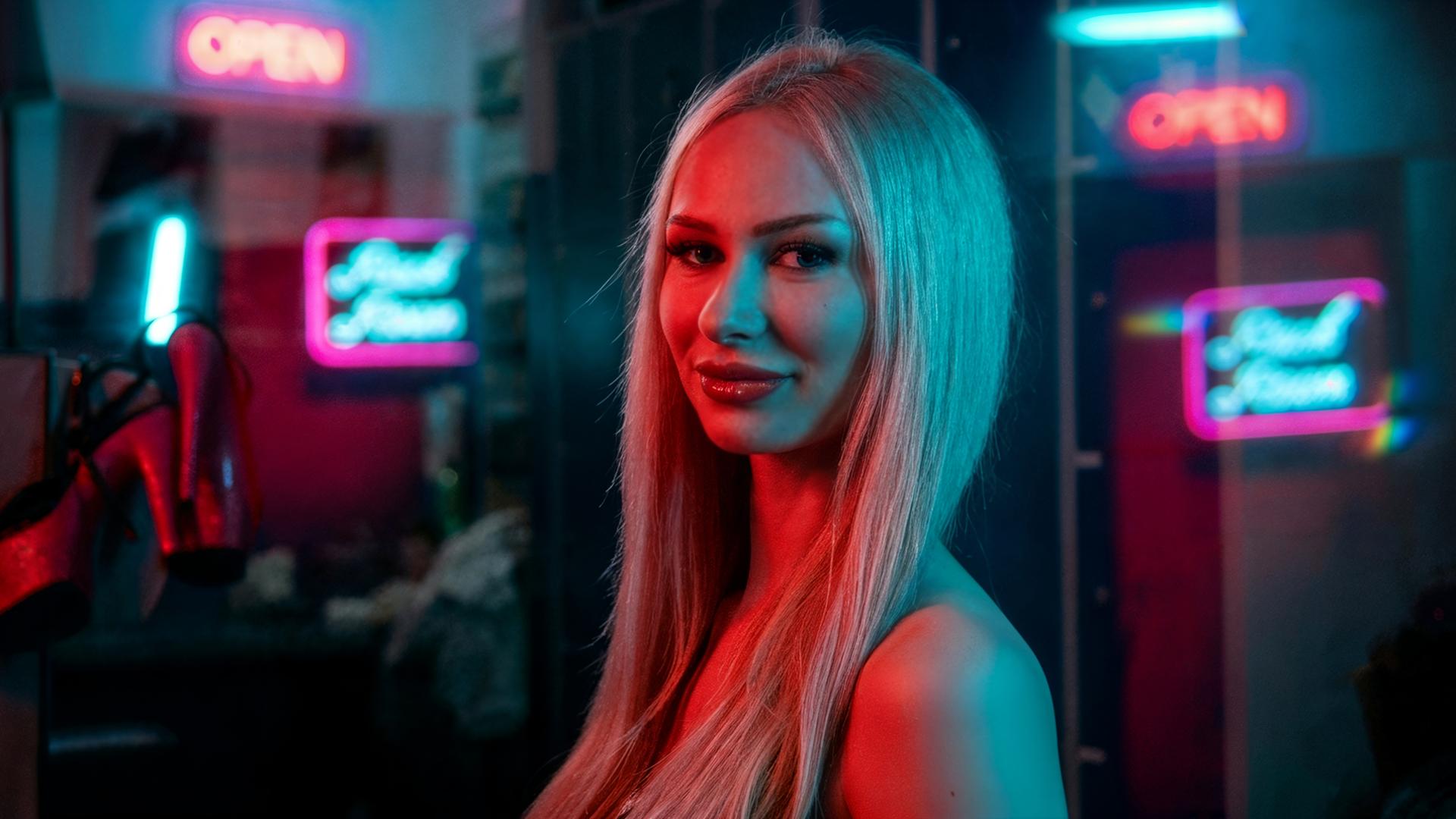 Eine junge Frau mit blonden langen Haaren schaut seitlich in die Kamera. Die Lichteffekte im Hintergrund wurden mit KI bearbeitet.  