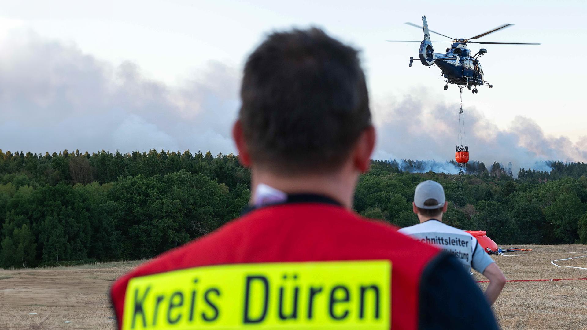 13.08.2026, Nordrhein-Westfalen, Hürtgenwald: Ein Löschhubschrauber ist bei einem Waldbrand im Hürtgenwald im Einsatz. 
