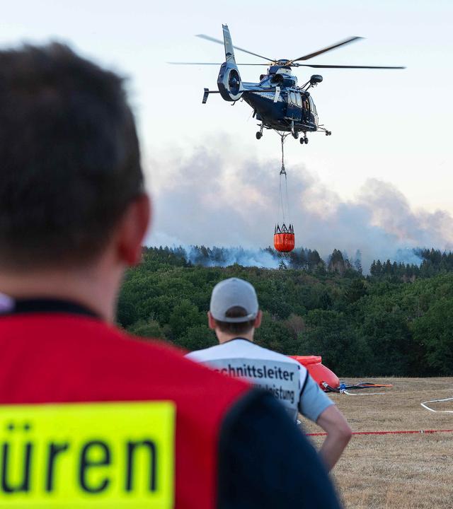13.08.2026, Nordrhein-Westfalen, Hürtgenwald: Ein Löschhubschrauber ist bei einem Waldbrand im Hürtgenwald im Einsatz. 