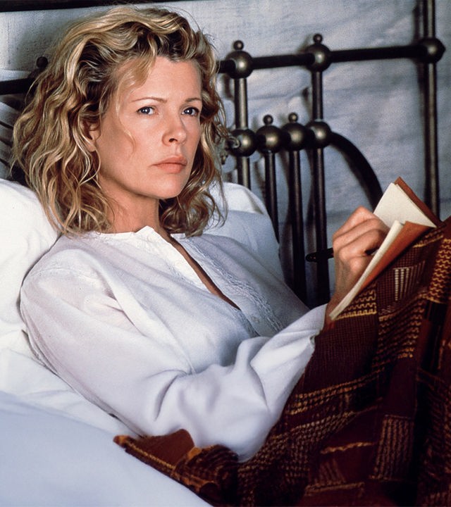  Kuki Gallmann (Kim Basinger) sitzt im Bett mit einem Notizbuch auf den Knien und blickt nachdenklich in die Ferne.