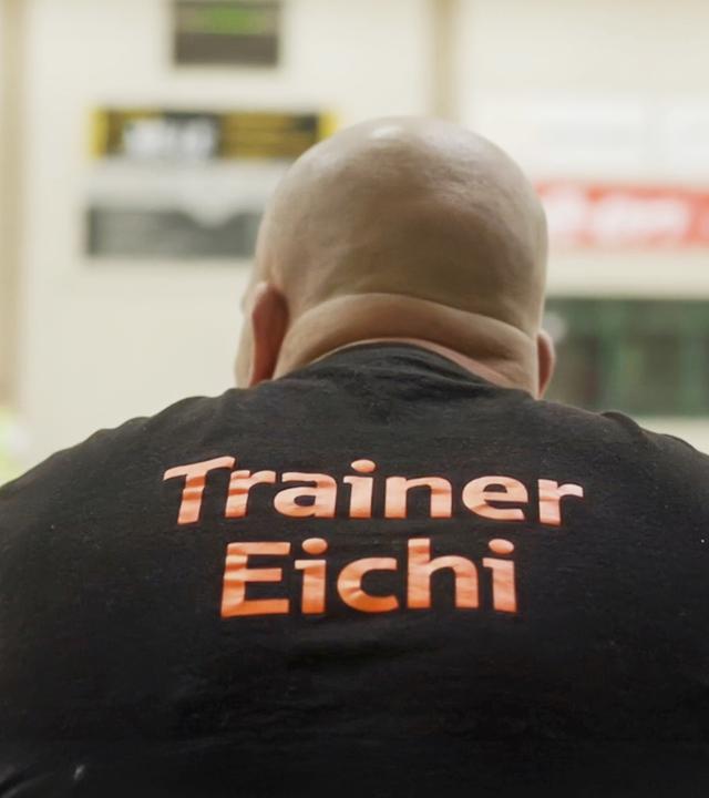 Eichi war als junger Erwachsener rechtsradikal. "Im Osten was Neues": Thomas "Eichi" Eichstätt sitzt als junger Erwachsener in den 90er Jahren auf einer Eckcouch. Graffitigekritzel befindet sich auf der Wand hinter ihm.
