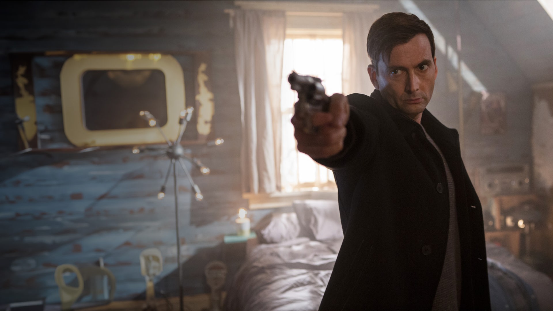 Cale Erendreich (David Tennant) steht mit gezogener Waffe in einem Schlafzimmer.