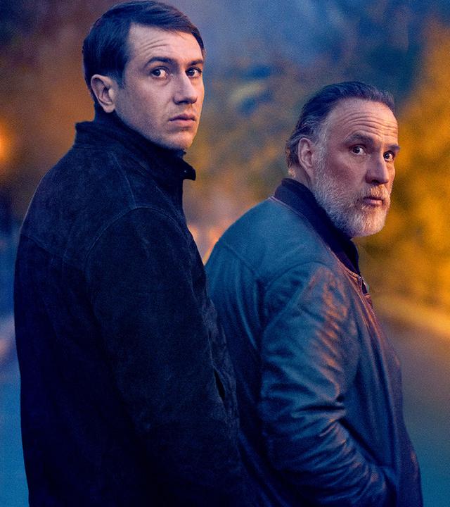 Yohan (Bastien Bouillon) und sein Kollege Marceau (Bouli Lanners) stehen bei Dunkelheit auf einer wenig beleuchteten Straße dicht nebeneinander. Beide schauen angespannt in die gleiche Richtung.