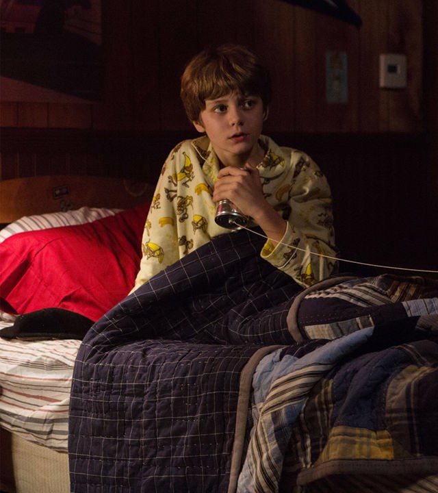 "Insidious: Chapter 2": Dalton (Ty Simpkins) sitzt ängstlich in seinem Bett und umklammert sein selbst gebasteltes Dosentelefon.