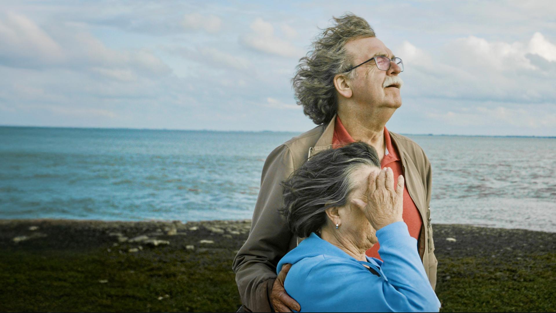 "Jenseits von Schuld": Ulla und Didi Högel stehen nebeneinander mit den Gesichtern dem Wind zugewandt am Strand.