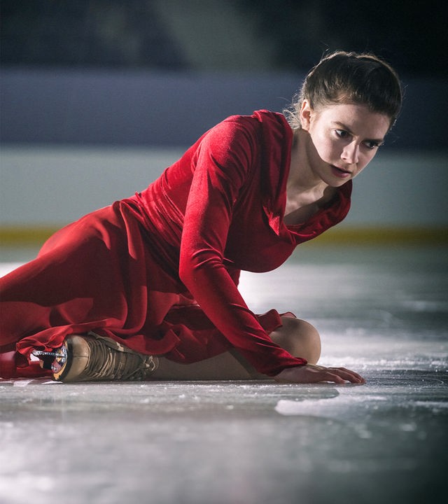 Kati Witt (Lavinia Nowak) sitzt nach einem Sturz auf der Eisfläche und stützt sich mit einer Hand ab.