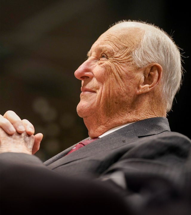 König Harald V. sitzt seitlich zur Kamera und lächelt.