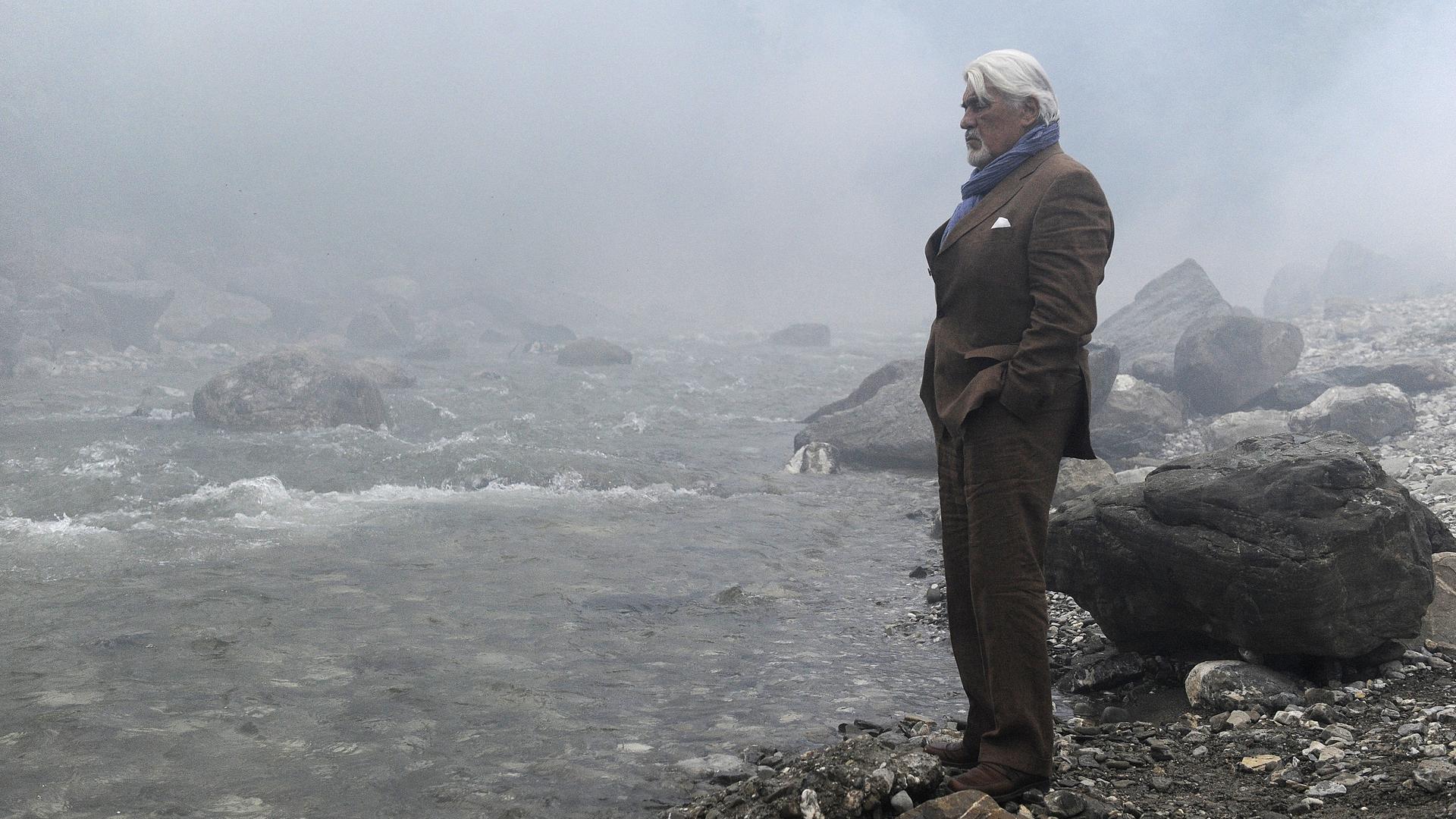 Richard (Mario Adorf) am Fluss, er hat seine Waffe dabei. 