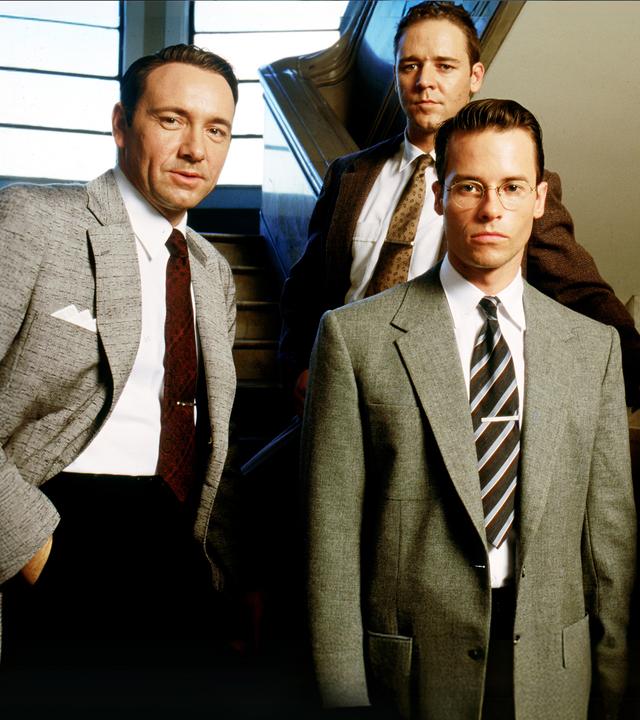 Jack Vincennes (Kevin Spacey), Bud White (Russell Crowe), Ed Exley (Guy Pearce) und Dudley Smith (James Cromwell) stehen auf einer Treppe und blicken nach vorne.