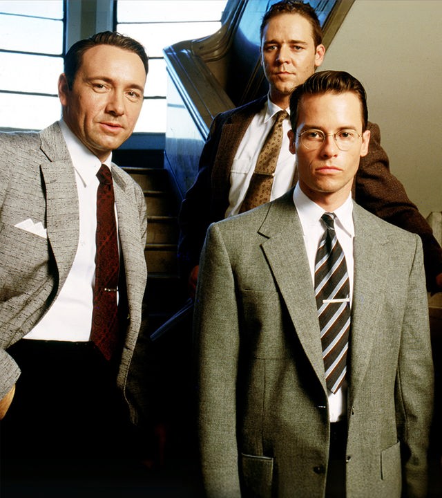 Jack Vincennes (Kevin Spacey), Bud White (Russell Crowe), Ed Exley (Guy Pearce) und Dudley Smith (James Cromwell) stehen auf einer Treppe und blicken nach vorne.