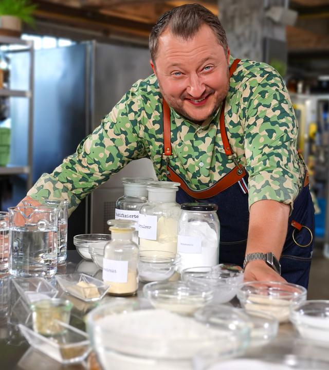 Sebastian Lege steht in seiner Werkstatt vor Produkten und Zutaten