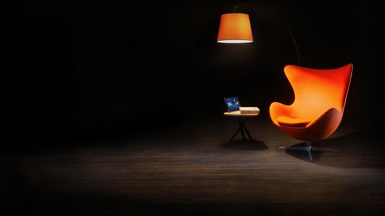 Ein Sessel, ein Beistelltisch und eine Leselampe auf einer sonst dunklen Bühne