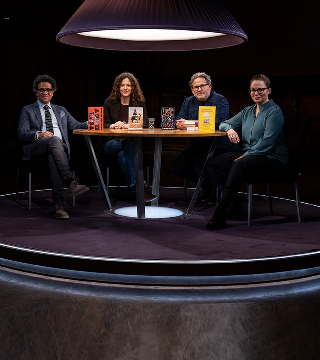 Ijoma Mangold, Sandra Richter, Wolfram Eilenberger und Gastgeberin Thea Dorn sitzen in einem dunklen Raum an einem Tisch und blicken in die Kamera. Sie werden von oben von einer Lampe beleuchtet.