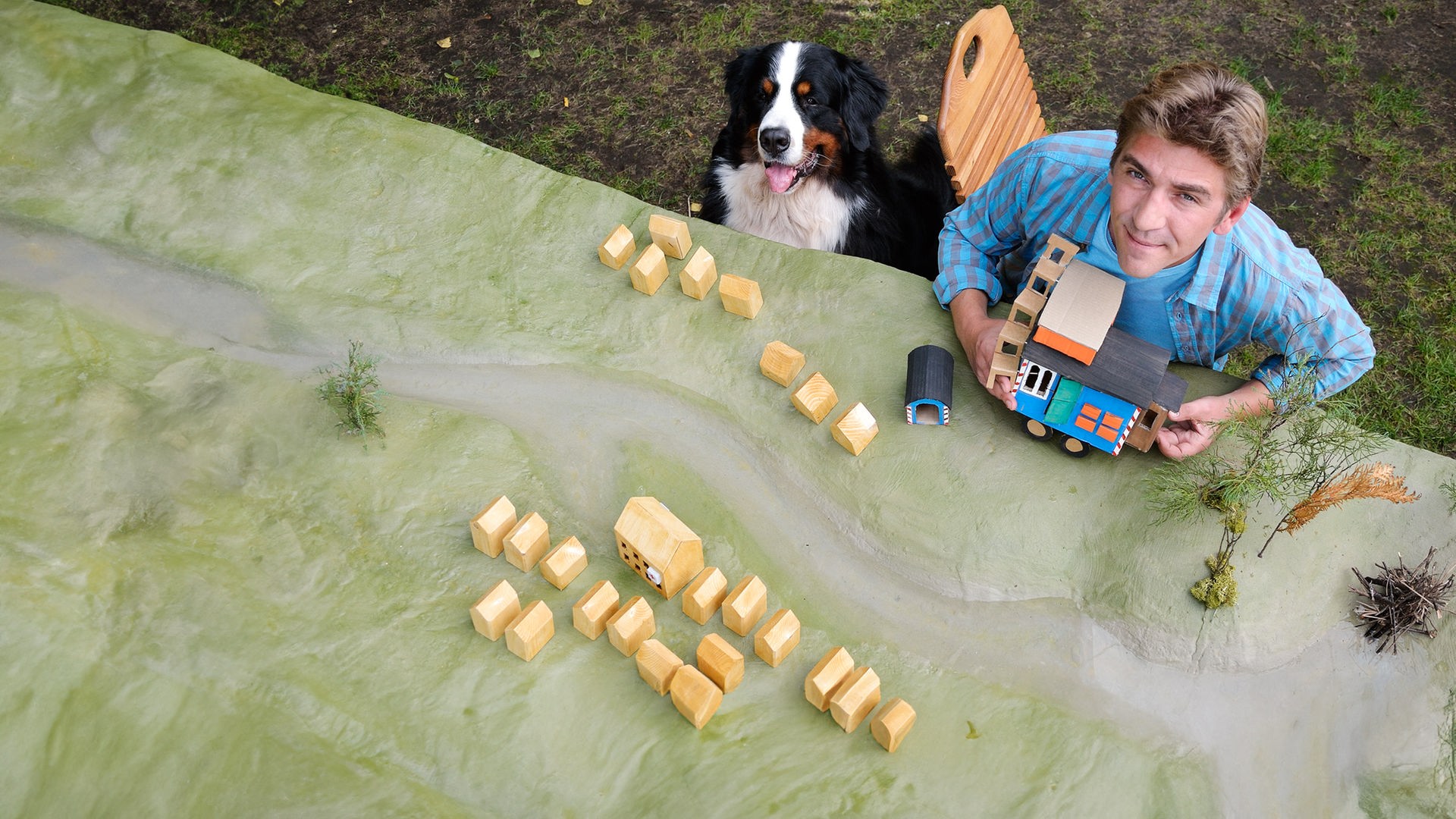 Fritz und Keks sitzen vor einem Modell von Bärstadt samt Bauwagen.