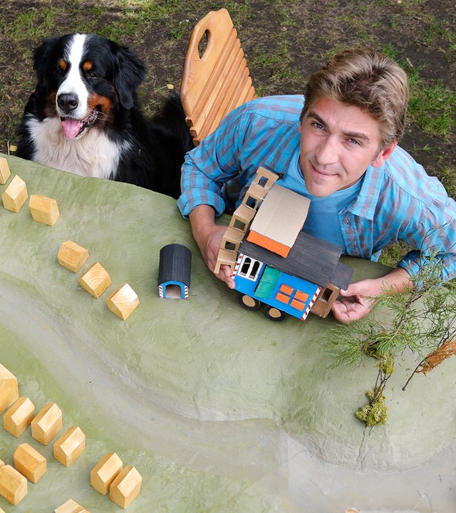 Fritz und Keks sitzen vor einem Modell von Bärstadt samt Bauwagen.