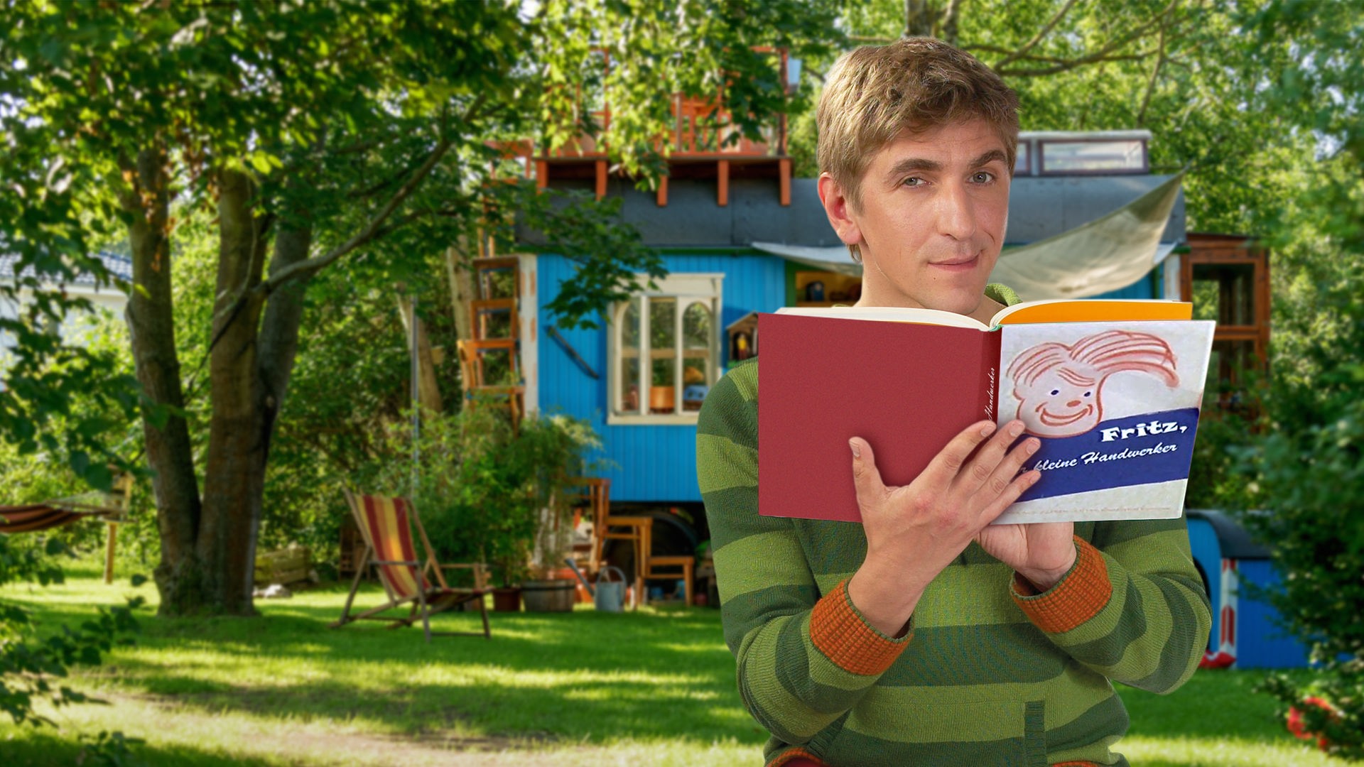 Fritz steht vor dem Bauwagen und hält ein Buch in den Händen