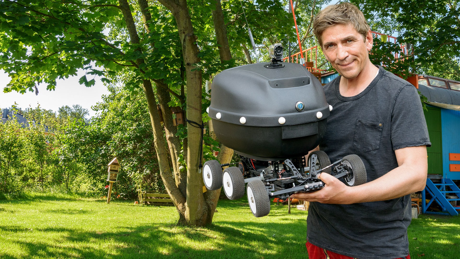 Fritz steht mit seinem selbstgebauten "Schlauto" vor dem Bauwagen