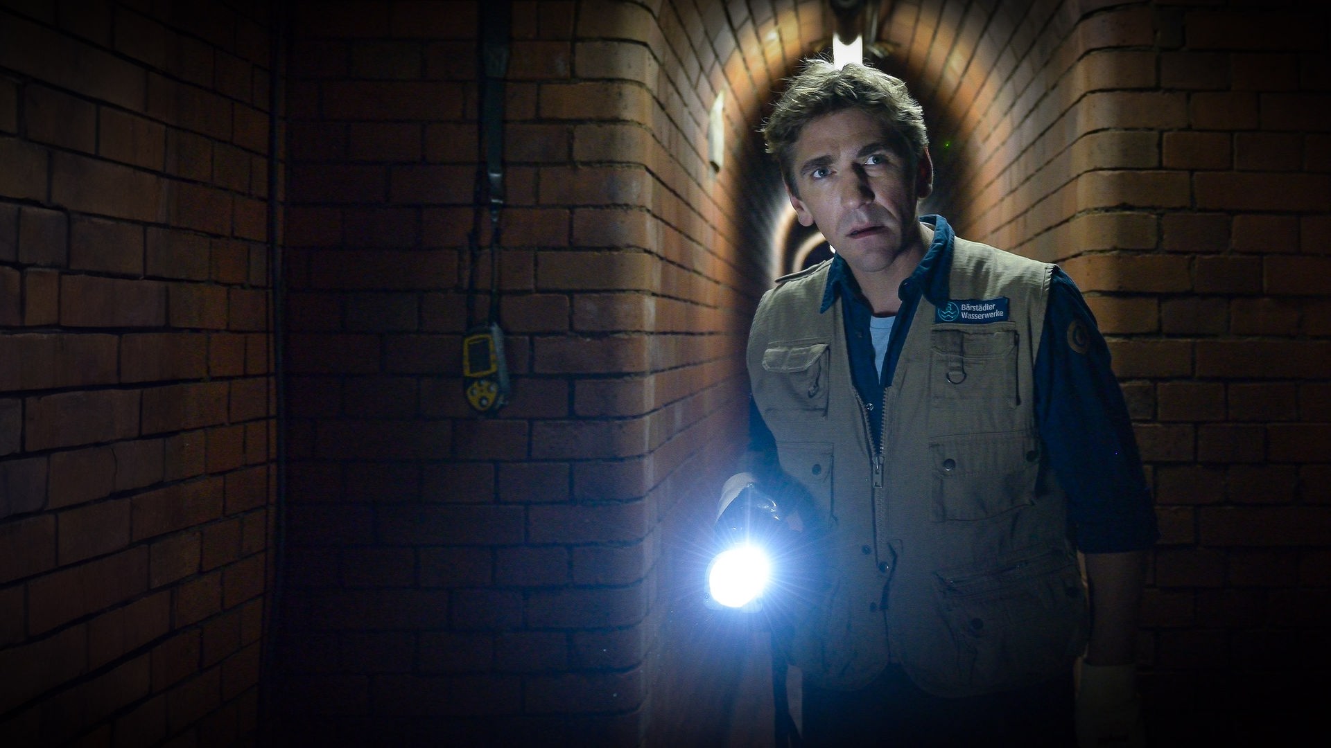 Fritz erkundet mit einer Taschenlampe in der Hand die Kanalisation