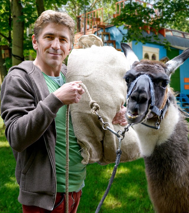 Fritz Fuchs steht mit einem Lama vor dem Bauwagen