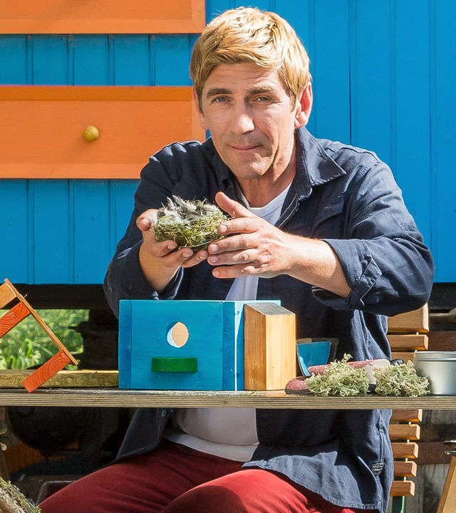 Fritz sitzt vor dem Bauwagen und hält ein Vogelnest in den Händen.