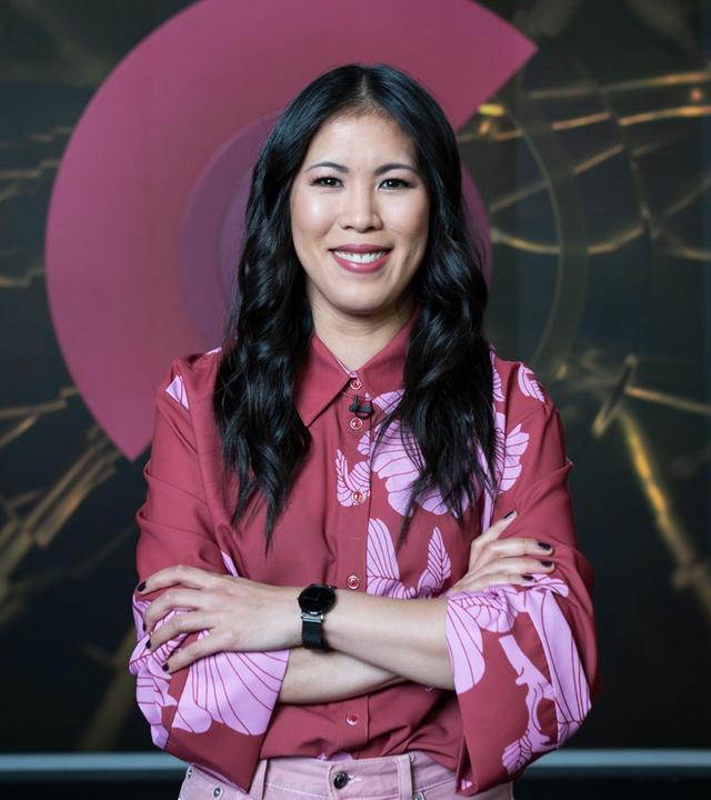 Mai Thi Nguyen-Kim steht verschränkten Armen auf der Bühne und schaut in Richtung Publikum.