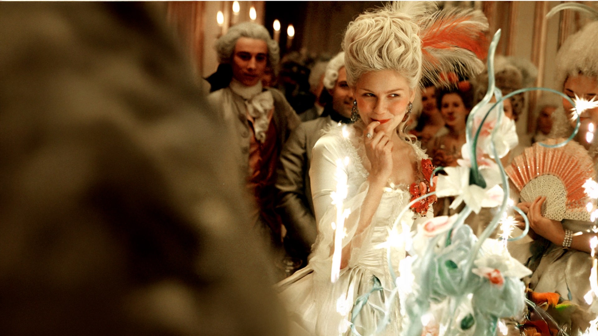 Marie Antoinette (Kirsten Dunst) grinst verschmitzt und fasst sich mit dem rechten Zeigefinger an die Lippe