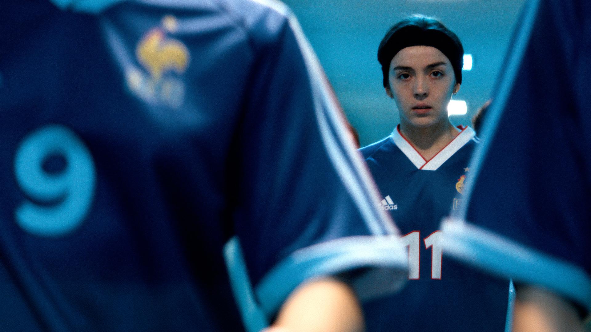Marinette (Garance Marillier) steht zwischen anderen Spielerinnen im Tunnel eines Stadions. Alle tragen das Trikot der Nationalmannschaft.