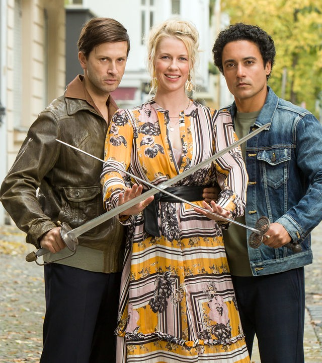 "Matze, Kebab und Sauerkraut": Noah (Franz Dinda), Charlottes (Christine Eixenberger) und Hakim (Omar El-Saeidi) sitzen gemeinsam am Tisch. Hakim hält Charlotte einen Teller hin, im Hintergrund glitzert der See.