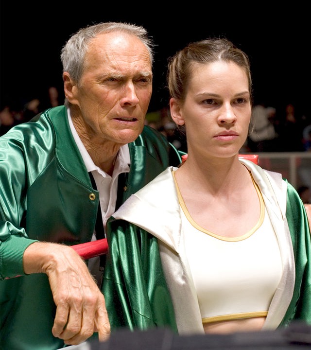 "Million Dollar Baby": Frankie (Clint Eastwood) steht hinter Maggie (Hilary Swank) in der Ecke eines Boxrings. Beide tragen grüne Trainings-Jacken und schauen entschlossen nach vorn.