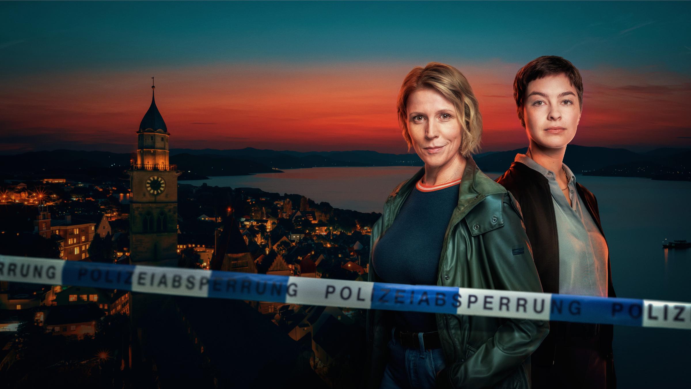 Die Ermittlerinnen Doro Beitinger (Franziska Weisz) und Chiara Locatelli (Maria Wördemann) stehen vor der abendlichen Kulisse der Stadt Überlingen am Ufer des Bodensees. Der Abendhimmel ist orange gefärbt. Im Vordergrund sieht man das Absperrband einer Crime-Scene. 