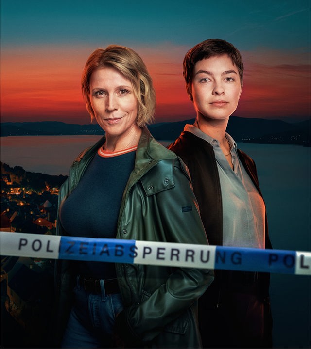 Die Ermittlerinnen Doro Beitinger (Franziska Weisz) und Chiara Locatelli (Maria Wördemann) stehen vor der abendlichen Kulisse der Stadt Überlingen am Ufer des Bodensees. Der Abendhimmel ist orange gefärbt. Im Vordergrund sieht man das Absperrband einer Crime-Scene. 