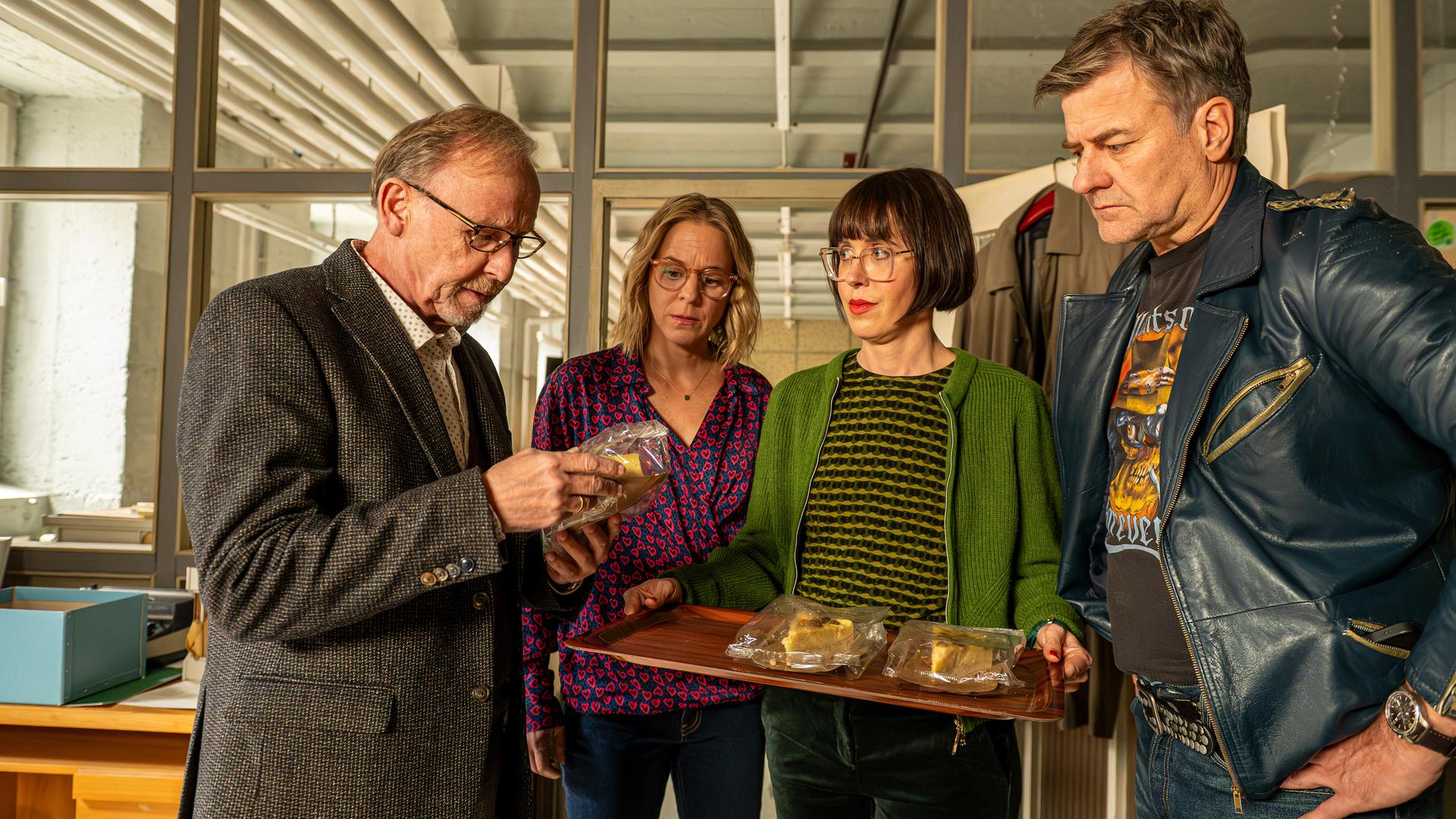 Ludwig Schaller (Alexander Held), Angelika Flierl (Bernadette Heerwagen), Dr. Linda Hösl (Eva Karl Faltermeier) und Harald Neuhauser (Marcus Mittermeier) stehen im Büro beisammen. Ludwig begutachtet einen Kuchen in seiner Hand. Die anderen drei beobachten ihn dabei, wobei Linda ein Tablet mit weiteren Kuchen in der Hand hält.
