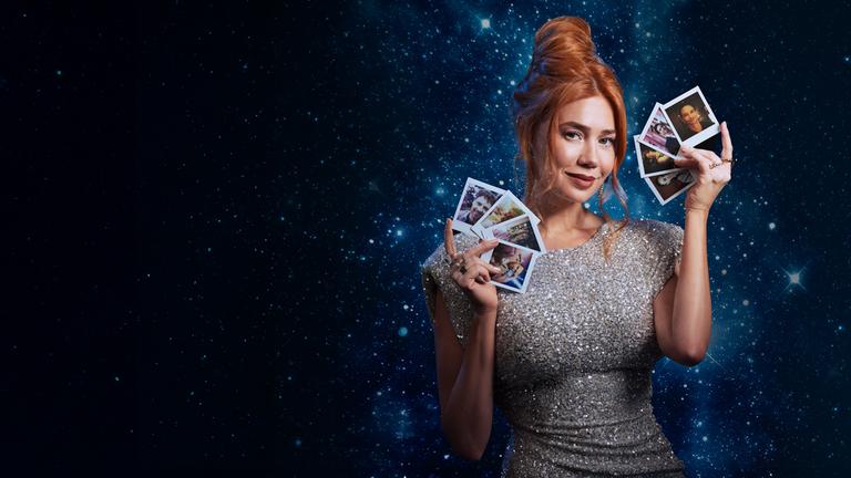 Ivy (Palina Rojinski) steht in einem langen roten Kleid vor einem großen roten Samtherz in dem einige Pfeile stecken. Sie hält einen Pfeil in ihren Händen.